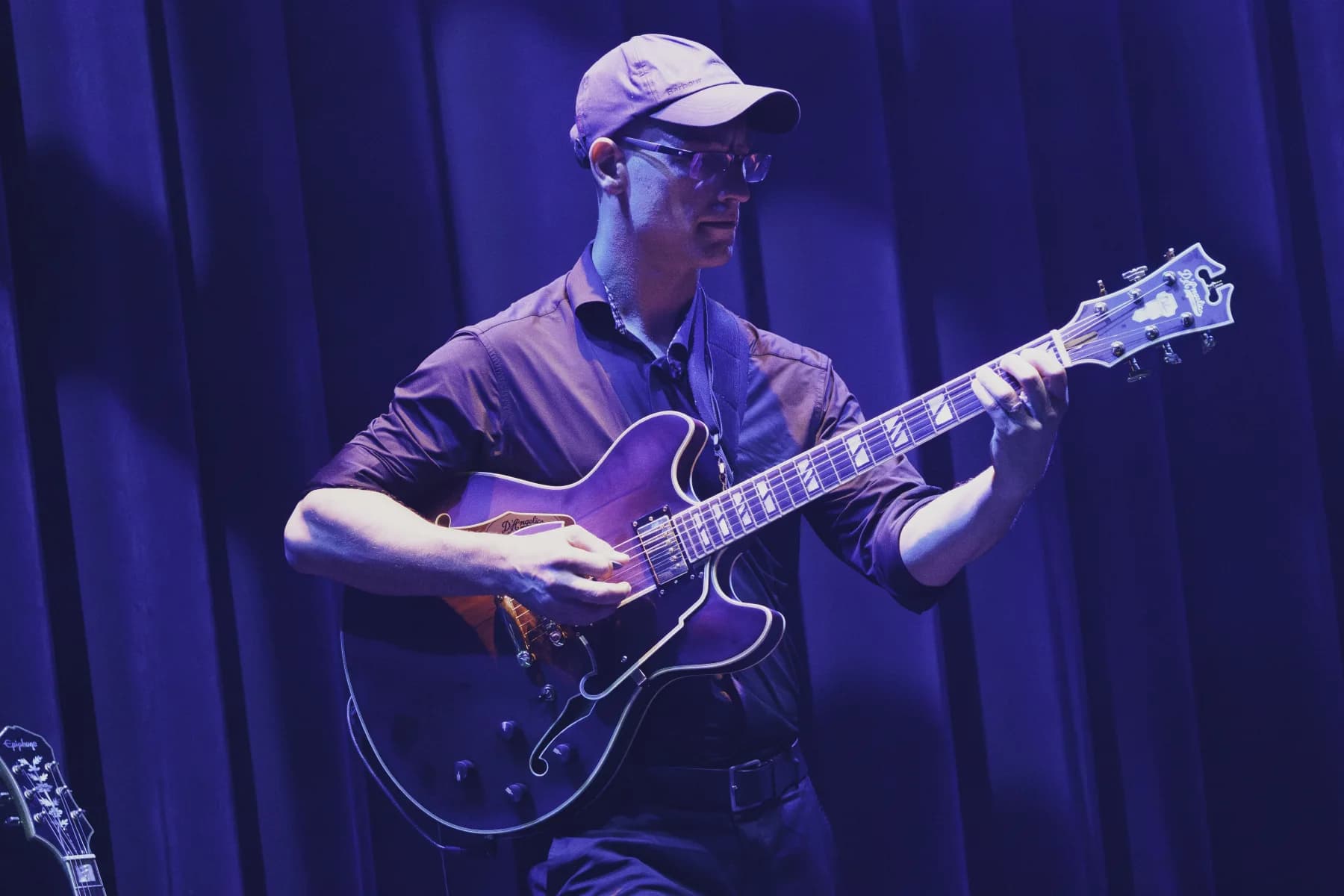 Pete Roth playing electric guitar under blue stage lighting.