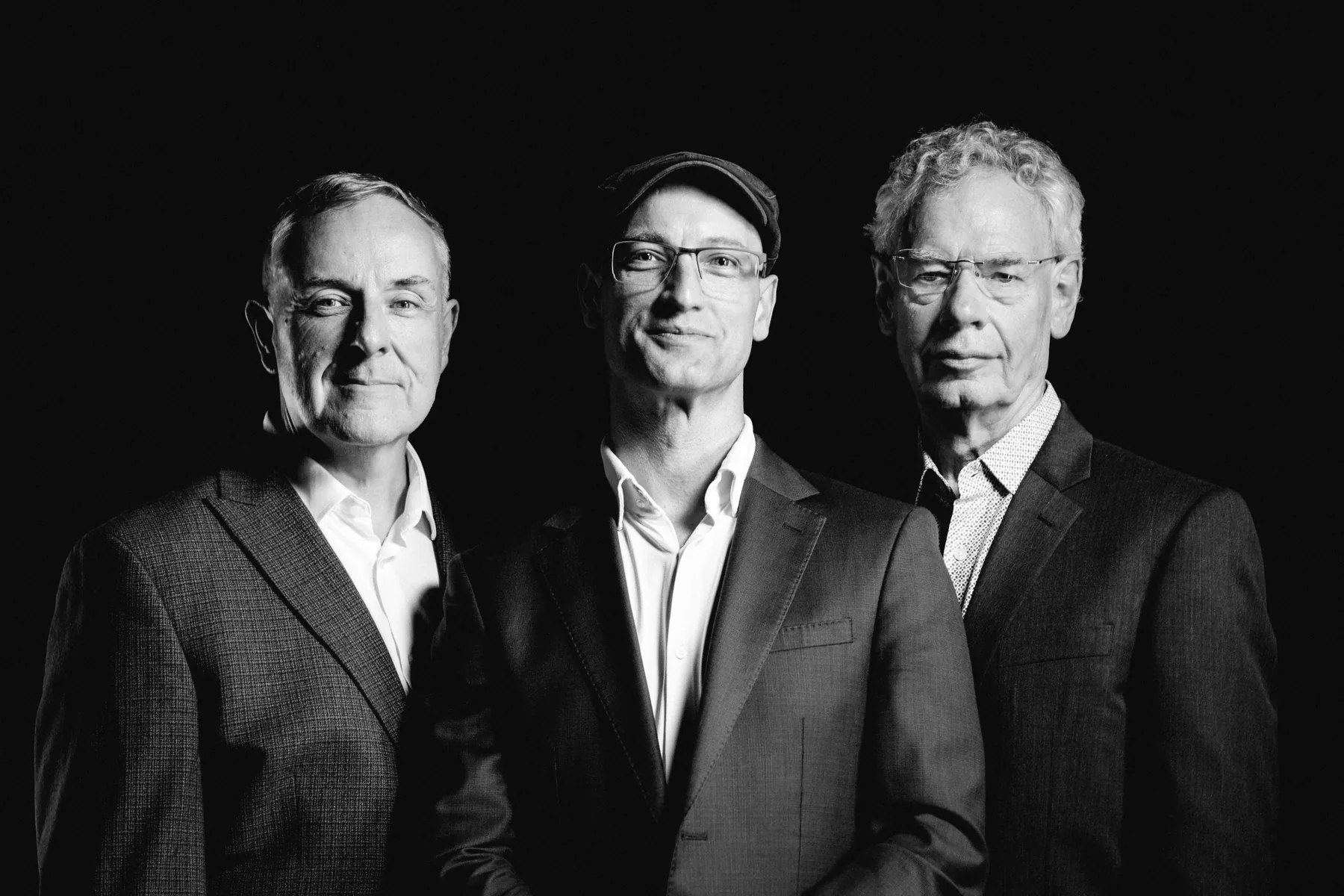 Pete Roth Trio smiling together in a relaxed black-and-white portrait.